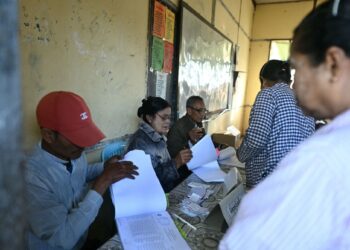 PETUGAS pilihan raya menyemak daftar pengundi penduduk yang tiba di pusat pengundian fasa kedua pilihan raya umum Myanmar di daerah Kawhmu, Yangon.-AFP