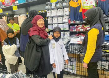NUR Farhana Nasuha (tengah) mencuba pakaian sekolah pada program sumbangan keperluan persekolah anjuran Thirdforce Pasir Mas di bawah Yayasan Raja Shamri di Mydin Mall Tunjong, Kota Bharu, Kelantan. – UTUSAN/ROSMIZAN RESDI