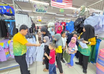 KANAK-kanak mencuba pakaian sekolah yang disumbangkan oleh ADUN Pangkor di Lumut semalam.  - UTUSAN/AIN SAFRE BIDIN