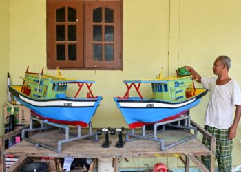 MOHD. Lazim Hassan bersama dua bot nelayan mini kawalan jauh yang dihasilkannya  di rumahnya di Kampung Telaga Daing, Kuala Terengganu, Terengganu. – UTUSAN/PUQTRA HAIRRY