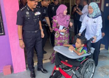 RUSMINI Ku Ahmad (kanan) menyantuni salah seorang pelajar Program Pendidikan Khas Intergrasi (PPKI) semasa melakukan tinjauan di Sekolah Menengah Kebangsaan (SMK) Dato Ali Ahmad bersempena hari pertama persekolahan di Kangar, Perlis hari ini. -UTUSAN/ASYRAF MUHAMMAD