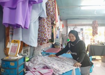 NORHAZIDA Che Harun menyiapkan tempahan baju raya pelanggan di kedainya di Gong Badak, Kuala Nerus, Terengganu. – UTUSAN/ERMA YUSNIDA JUSOH