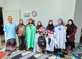 NAZLINA Omar (dua dari kiri) dan suaminya bersama lima anak saudara mereka menunjukkan pakaian dan kelengkapan sekolah yang dibeli menggunakan BAP ketika ditemui di Sungai Manik, Pasir Salak, Perak. 
– UTUSAN/AIN SAFRE BIDIN