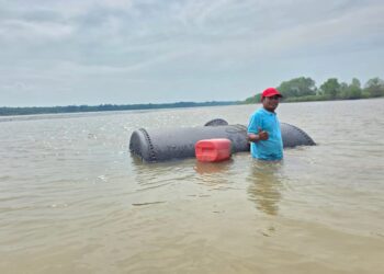 PEMANDU bot sewa, Rozy Mat Akhir menunjukkan objek besi yang terdapat di Sungai Perak di Teluk Intan, Perak. - MINGGUAN/AIN SAFRE BIDIN