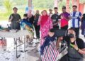 NORSARFINAZ Mohd Azman (tengah) bersama ibu bapa dan kanak-kanak menyertai Program Gunting Rambut Percuma sempena Kembali Ke Sekolah di Galeri Mat Kilau, Kampung Bukit Jerantut baru-baru ini.
