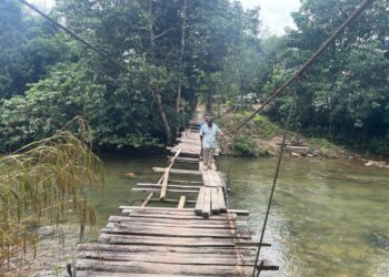 DUA penduduk terpaksa melalui titi gantung di Kampung Chatel Damai, Lata Rek, Kelantan yang runtuh Khamis lalu untuk melakukan urusan harian mereka.