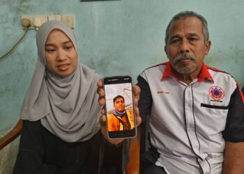 MOHD. Zain Daud bersama anaknya menunjukkan gambar Amirrulmukminin yang mendermakan organ semasa ditemui pemberita di Perumahan Desa Darulnaim, Pasir Tumbuh, Kota Bharu, Kelantan.-UTUSAN/YATIMIN ABDULLAH.