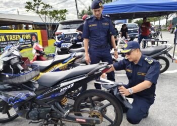 MOHAMMAD Yusoff Abustan memeriksa motosikal yang disita dalam operasi di Jalan Sultan Azlan Shah, Ipoh, Perak hari ini.