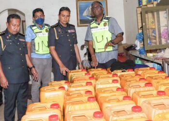 S. JEGAN (kanan) menunjukkan sebahagian daripada tong berkapasiti 17kg yang mengandungi minyak masak bersubsidi dalam satu serbuan di sebuah rumah tidak berpenghuni di Jalan Pekan Darat, Butterworth, Pulau Pinang hari ini.-UTUSAN/DANIAL SAAD