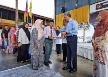 MOHAMAD Hasan menyampaikan sumbangan kepada para pelajar di Majlis Penyerahan Bantuan Awal Persekolahan SMK Seri Sendayan, Seremban hari ini. - UTUSAN/MOHD. SHAHJEHAN MAAMIN