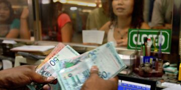 SEORANG pengurup wang mengira wang kertas ringgit Malaysia sementara pelanggan menunggu di kiosk pengurup wang di Kuala Lumpur. - AFP