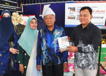 RAHMAD Mariman menunjukkan Buku Kampung Kita Mukim Kandang yang dilancarkan di Sekolah Kebangsaan (SK) Bendahara Seri Maharaja, Kandang, Melaka, hari ini. - UTUSAN/AMRAN MULUP