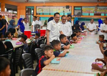ZAINAL Abas (berdiri, kiri) beramah mesra dan menyantuni murid tahun satu semasa mengadakan sesi libat urus pembukaan sekolah peringkat negeri di Sekolah Kebangsaan (SK) Gong Tok Nasek, Kuala Terengganu. -UTUSAN/PUQTRA HAIRRY
