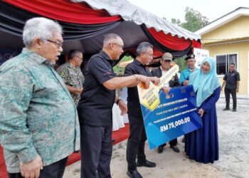 ADLY Zahari (tengah) menyerahkan replika kunci rumah kepada balu veteran ATM, Ruslinda Zakaria, pada Majlis Penyerahan Kunci Rumah Bina Baharu Program Inisiatif Perumahan Veteran ATM Peringkat Negeri Sembilan di Kampung Sentosa, Paroi, Seremban hari ini. - UTUSAN/MOHD.SHAHJEHAN MAAMIN