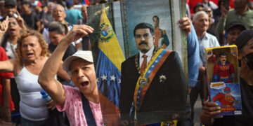 SEORANG wanita memegang potret Maduro semasa perhimpunan di Caracas selepas tentera AS menangkapnya dalam operasi ketenteraan pada Sabtu. - AFP