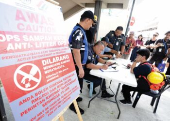 ZAINAL Fitri Ahmad (kiri) memerhatikan seorang pejalan kaki yang diberikan notis dalam Operasi Penguatkuasaan Kesalahan Membuang Sampah Kecil di Jalan Tun Abdul Razak, Johor Bahru, Johor semalam. 
– UTUSAN/RAJA JAAFAR ALI