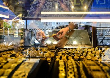 Seorang pekerja memegang barang kemas di sebuah kedai emas di Banda Aceh, Indonesia. - AFP