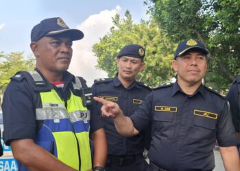 MOHD. Azmi  Jaafar  (kanan) menunjukkan kamera badan yang dipasang pada anggota penguat kuasa ketika Operasi Khas Sembilan Kesalahan Utama di Jalan Kuala Kangsar-Jalan Sultan Azlan Shah dekat Tasek hari ini.