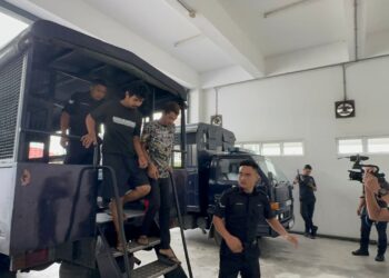 ANGGOTA polis membawa Wan Azmir Wan Aznam (kiri) dan Haris Shafie di Mahkamah Sesyen Kota Bharu, Kelantan. - UTUSAN/ROSALWANI CHE SOH