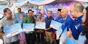 AARON Ago Dagang (tengah) menyampaikan cek cura kepada 10 KRT melalui Program Satelit Komuniti Rakyat Madani Tahun 2026 (Kluster Jabatan Perpaduan Negara dan Integrasi Nasional) Peringkat Negeri Perak di Pusat Nadi Kampung Dato' Ahmad Said Tambahan 2, di Ipoh hari ini.