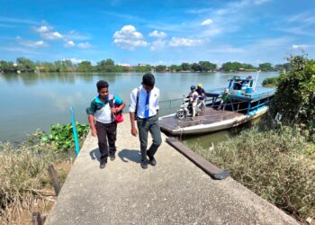 G. JAYANESH (kiri)  dan Yuugan menaiki bot penambang menyeberang Sungai Perak untuk pulang dari sekolah ke rumah mereka di sebuah estet di Teluk Intan, Perak. – UTUSAN/AIN SAFRE BIDIN
