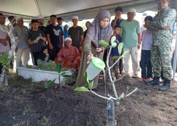 SITI Hajar Ismail menyiram pusara Muhammad Zarif Hazahari di Tanah Perkuburan Islam Batu Rakit, Kuala Nerus, Terengganu. - UTUSAN/ERMA YUSNIDA JUSOH