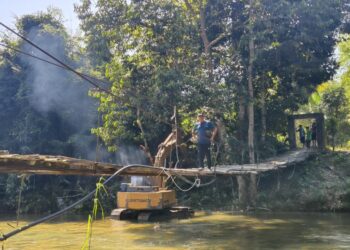 KERJA-kerja pembersihan tapak bagi membina jambatan besi menggantikan titi gantung yang runtuh di Kampung Chatel Damai, Kuala Krai, Kelantan. - UTUSAN/YATIMIN ABDULLAH