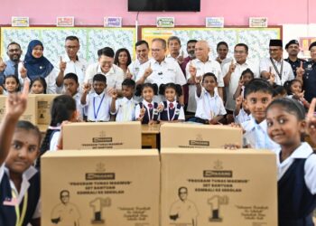 Wan Rosdy Wan Ismail (tengah) bersama pelajar Sekolah Jenis Kebangsaan Tamil (SJKT) Bentong yang menerima Kit Tunas Makmur yang set lengkap peralatan pembelajaran antaranya beg sekolah dan alat tulis lain.  – UTUSAN/SHAIKH AHMAD RAZIF