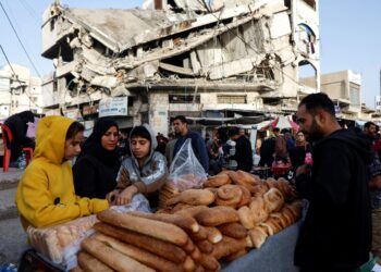 PENDUDUK Palestin menjual roti di tepi runtuhan bangunan pada hari pertama Ramadan di Gaza City, kelmarin. - AFP
