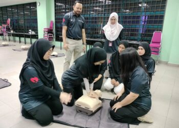 Dr. Mohd Hisham Mohd Isa (berdiri) dan Dr. Ruslinda Mustafar (berdiri) memerhatikan peserta mempraktikkan tekanan dada.