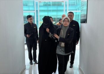 TERTUDUH (dua dari kiri) dibawa keluar dari Mahkamah Sesyen Kangar, Perlis, selepas menghadapi lima pertuduhan pecah amanah hari ini. -UTUSAN/ASYRAF MUHAMMAD