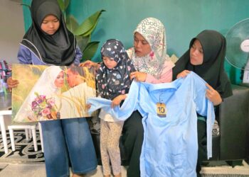 NUR Azura Ahmad dan anak-anaknya menunjukkan baju Melayu berwarna biru yang tidak sempat dipakai Allahyarham Koperal Mohd. Pozli Jaudin ketika ditemui di Taman Rapat Permai di Ipoh. – UTUSAN/AIN SAFRE BIDIN
