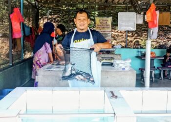 MUHAMMAD Isa Ali menunjukkan ikan patin yang dijualnya di Jerantut Feri di Jerantut, Pahang.