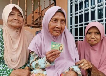 ATIMAH Narijan menunjukkan kad pengenalan yang menunjukkan usianya mencecah 103 tahun pada tahun ini sambil ditemani dua anaknya di Kampung Tanjung Sari, Teluk Intan. – UTUSAN/AIN SAFRE BIDIN