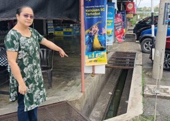 N. AMUTHA menunjukkan longkang yang tidak bertutup di hadapan premis perniagaan di Bandar Baharu Inderapura, Jerantut, Pahang. 
– mingguan/HARIS FADILAH AHMAD