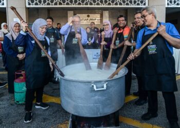 TENGKU Ampuan Pahang, Tunku Azizah Aminah Maimunah Iskandariah (kiri) bersama Abdul Rashid Hussain (dua dari kiri) mengacau bubur lambuk pada Program Rewang Bubur Lambuk UIAM di Gombak, Selangor kelmarin. – UTUSAN/SYAKIR RADIN