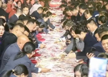 PEKERJA syarikat Henan Kuangshan Crane Co., Ltd merebut wang tunai yang diletakkan di atas meja ketika majlis pemberian bonus akhir tahun di China.-AFP