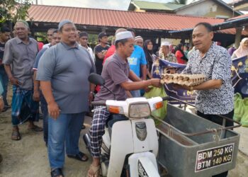 MOKHTAR Ismail menaiki motosikal roda tiga ketika menerima sumbangan di Kampung Kajang Sebidang, Tumpat, Kelantan. 
– UTUSAN/ROHANA ISMAIL
