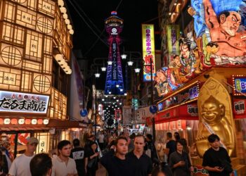 GAMBAR fail menunjukkan pelancong memenuhi laluan utama di kawasan Shinsekai berlatarbelakangkan Menara Tsutenkaku di Osaka.- AFP