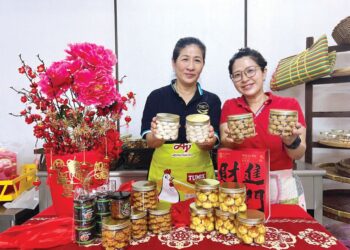 Tan Li Er (kiri) dan anaknya, Tan Vin Shi menunjukkan antara kuih dan biskut yang dihasilkan sempena Tahun Baharu Cina di kedainya di Kuala Perlis, Perlis, semalam. – UTUSAN/ASYRAF MUHAMMAD