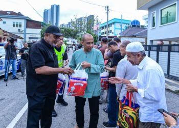 Jawahar Ali Taib Khan (kiri) menyerahkan produk Gardenia kepada orang ramai sempena Ramadan di Maahad Tahfiz Al-Madrasathul Faridiyah Kuala Lumpur semalam. –MINGGUAN/SYAKIR RADIN