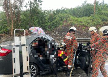 PASUKAN bomba mengeluarkan kedua-dua mangsa yang tersepit selepas kereta dinaiki mereka dihempap sebatang pokok tumbang akibat hujan lebat di jalan menghala ke Kolej INTI, Nilai, Seremban petang tadi. – GAMBAR / IHSAN POLIS