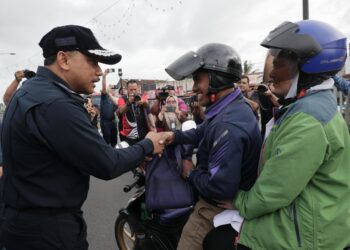 MOHD. Yusoff Mamat (kiri) menyantuni pengguna jalan raya semasa melancarkan Kempen Kesedaran dan Keselamatan Jalan Raya sempena Ops Selamat di Pasir Pekan, Tumpat, Kelantan hari ini-UTUSAN/KAMARUL BISMI KAMARUZAMAN.
