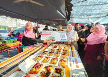 FUZIAH Salleh (kanan) menyerahkan kad diskaun kepada peniaga di Bazar Ramadan Mydin Mall, Tunjong, Kota Bharu, Kelantan hari ini-UTUSAN/YATIMIN ABDULLAH.