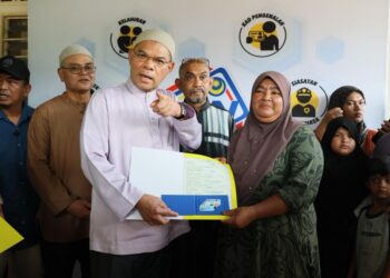 SAIFUDDIN Nasution Ismail (kiri) menyampaikan Mykad dan sijil kelahiran kepada sembilan sekeluarga menerusi Program Program Menyemai Kasih Rakyat (MEKAR) Jabatan Pendaftaran Negara (JPN) di Kampung Kampung Simpol Belubang, Machang, Kelantan hari ini-UTUSAN/KAMARUL BISMI KAMARUZAMAN.