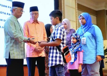 AL-SULTAN Abdullah Ri'ayatuddin Al-Mustafa Billah Shah (kiri) menyampaikan kurniaan sumbangan kepada anak-anak Yayasan Keluarga Malaysia pada Majlis Berbuka Puasa yayasan itu di Hotel Grand Darul Makmur di Kuantan, Pahang. - FOTO/SHAIKH AHMAD RAZIF