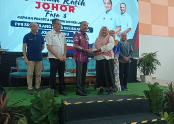 Mohd. Jafni (tengah) menyampaikan Bantuan Kasih Johor Fasa 3 kepada penerima di Dewan PPR Sri Stulang, Johor Bahru, hari ini. - UTUSAN
