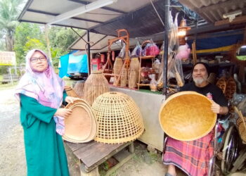 AZMAN Yahya (kanan) bersama produk kraftangan yang dijual di gerainya di Kampung Sungai Bari, Setiu, Terengganu. – UTUSAN/WAN ZURATIKAH IFFAH WAN ZULKIFLI
