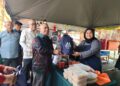 SAARANI Mohamad menyampaikan apron kepada peniaga ketika mengadakan walkabout ke Bazar Ramadan Stadium Perak, Ipoh hari ini.