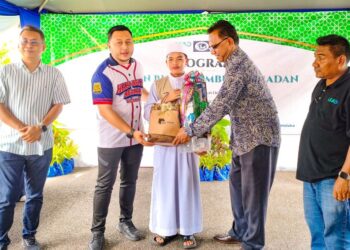 MUHAMMAD Irsyaad Mohd. Shahrol Anuar menerima sumbangan yang disampaikan Mohd. Ridhwan Mohd. Ali pada Program Agihan Bubur Lambuk Ramadan anjuran Lead, WYF dan Pendika di Masjid Sayyidina Ali, Bukit Katil, Melaka, semalam. - UTUSAN/AMRAN ALI